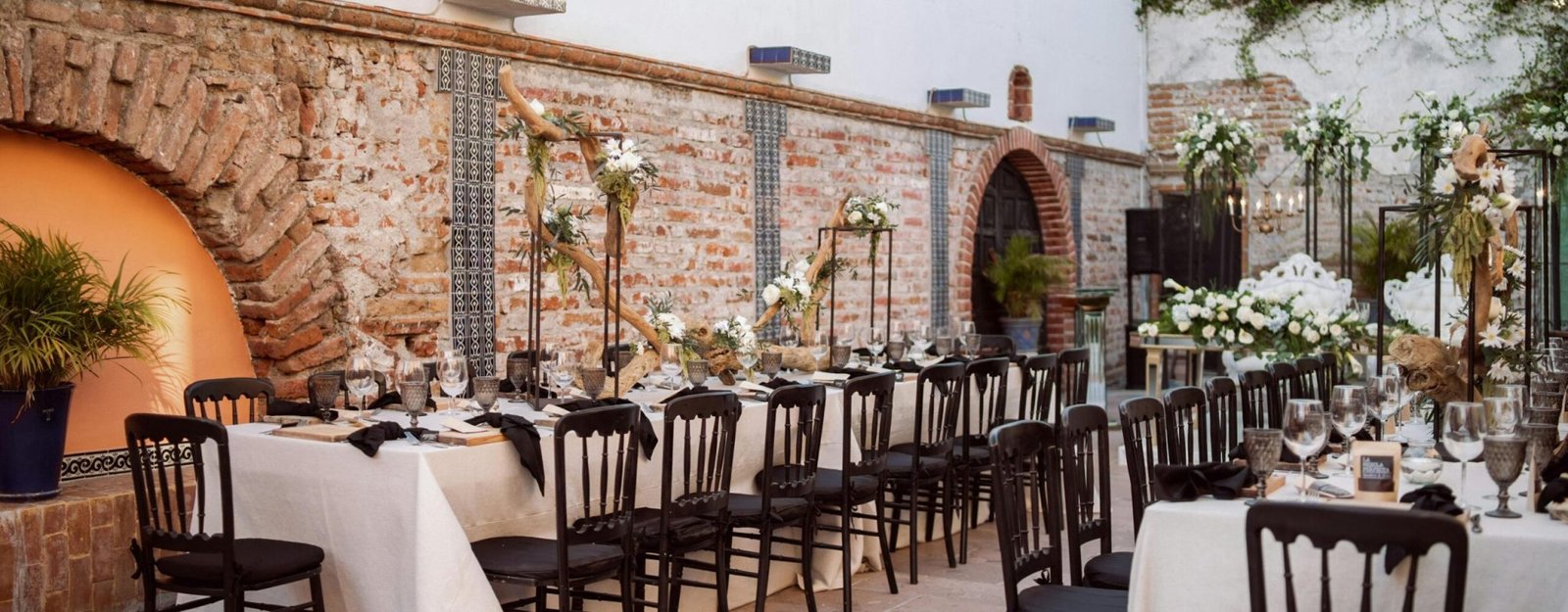 Chic outdoor wedding venue with decorated tables, chairs, and floral arrangements.