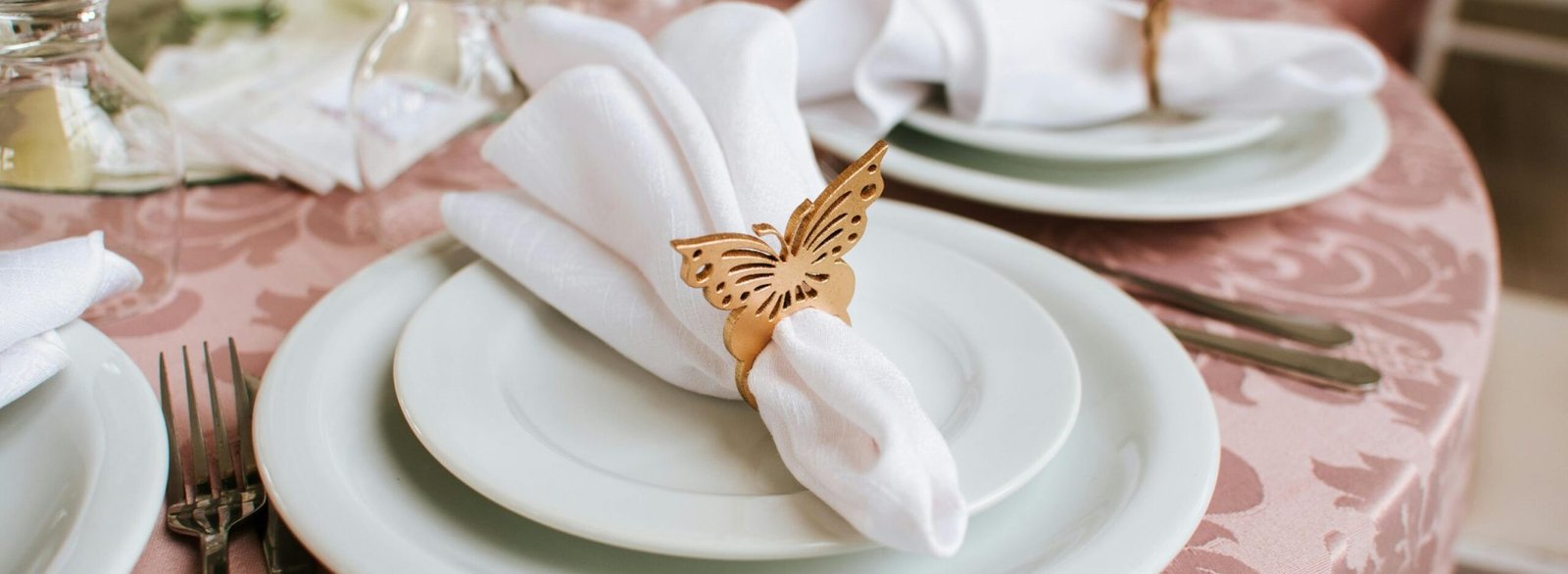 Sophisticated wedding table setting featuring butterfly napkin rings, fine china, and elegant tableware.